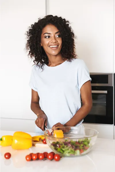 BPC-157-Peptide-Therapy-Treatment A smiling black woman prepares a healthy salad. Get BPC-157 Peptide Therapy from Anita Petruzzelli, M.D. in Glastonbury.