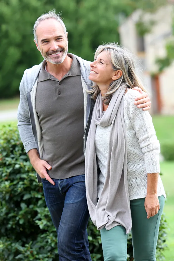 Bioidentical-Hormone-Therapy-Treatment A mature couple in gray toned clothes and jeans walk happily outside, happy with their successful bioidentical hormone treatments from Anita Petruzzelli, M.D. in Glastonbury.