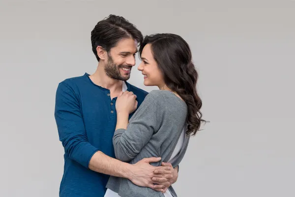 Erectile-Dysfunction-Doctor A man in a blue shirt embracing a woman in a gray shirt smiles due to his successful erectile dysfunction care from Anita Petruzzelli, M.D. in Glastonbury.