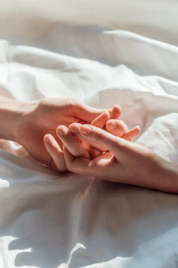 Female-Sexual-Dysfunction-Treatment Close-up of a couple holding hands in bed. Get medications for female sexual dysfunction from Anita Petruzzelli, M.D. in Glastonbury.