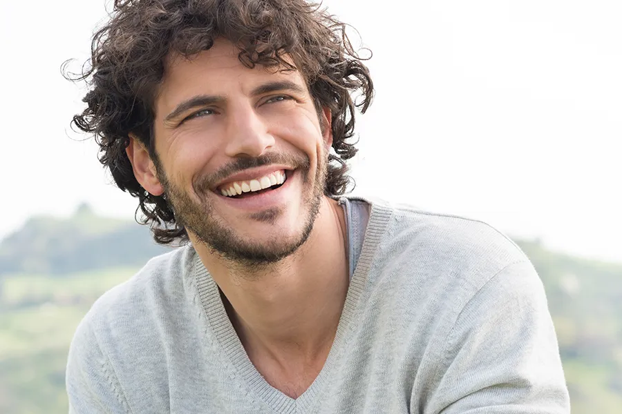 Hair-Loss-Clinic A man with radiant curly hair and a confident smile looks to the horizon. Anita Petruzzelli, M.D. in Glastonbury offers effective therapies to support hair regrowth and scalp health to treat hair loss.