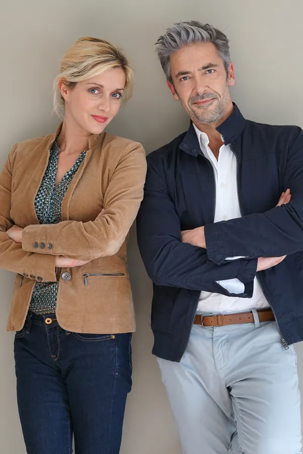 Hyperthyroidism-Treatment A middle-aged couple stand against a wall smiling with folded arms. Get hyperthyroidism treatment from Anita Petruzzelli, M.D. in Glastonbury.