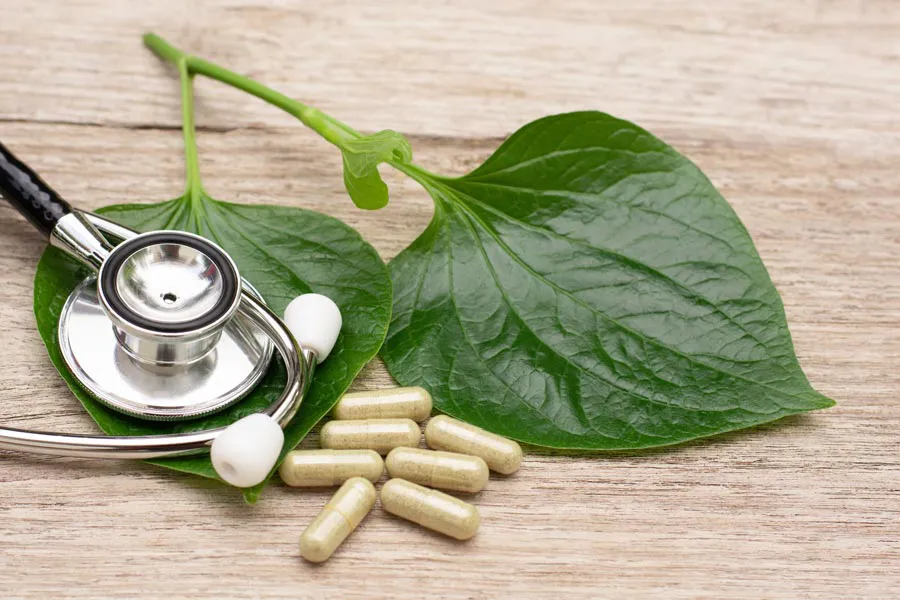 Integrative-Medicine-Clinic A stethoscope, leaves, and medicine capsules on a wood table, representing Integrative Medicine provided by Anita Petruzzelli, M.D. in Glastonbury.