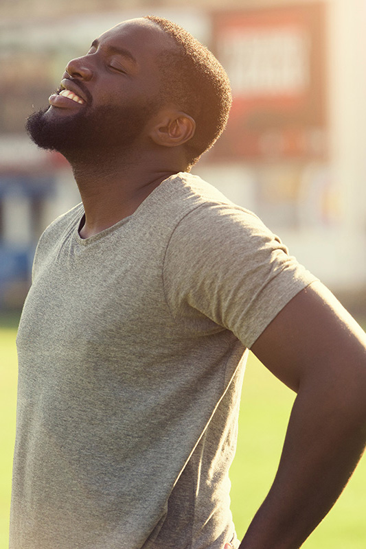 Lean-Muscle-and-Recovery-Treatment A black man in a gray t-shirt and smiles, looking up with closed eyes after a satisfying workout. Get treatment for lean muscle loss and recovery from Anita Petruzzelli, M.D. in Glastonbury.