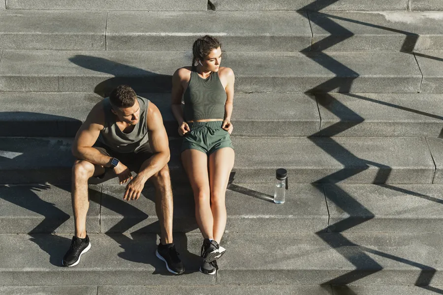 Medical-Weight-Loss-Doctor A couple in gray and green track clothes resting after a workout on stone steps, happy with their weight loss plans from Anita Petruzzelli, M.D. in Glastonbury.