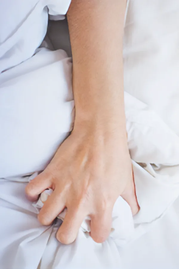Medications-for-Painful-Intercourse-Treatment Close-up of a woman's hand gripping sheets on a bed. Get medications for painful intercourse from Anita Petruzzelli, M.D. in Glastonbury.