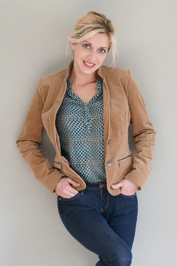 Metabolic-Syndrome-Treatment A smiling blonde woman in a tan leather jacket leans against a gray wall. Schedule metabolic syndrome from Anita Petruzzelli, M.D. in Glastonbury.