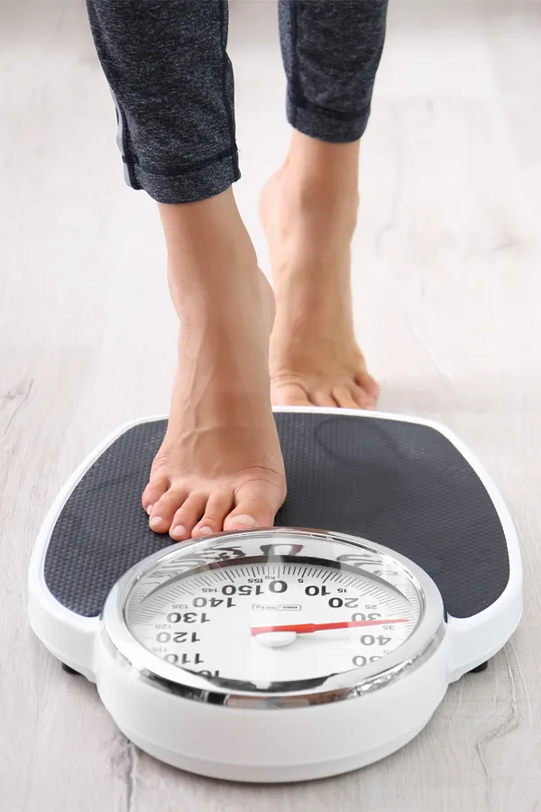 Obesity-Treatment Close up of feet stepping onto a scale. Receive expert functional medicine for obesity treatment by Anita Petruzzelli, M.D. in Glastonbury.