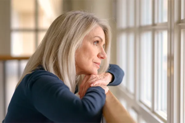 PMDD-Specialist A middle-aged woman with with a somber expression stares out the window. Get treatment for Premenstrual Dysphoric Disorder from Anita Petruzzelli, M.D. in Glastonbury.