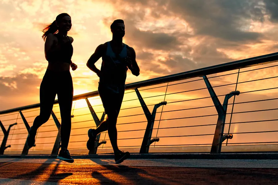 Performance-Enhancing-Peptides-Doctor A couple jogging on a bridge at sunrise, representing performance enhancing peptide therapy from Anita Petruzzelli, M.D. in Glastonbury.