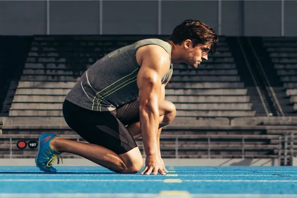 Sermorelin-Clinic With a determined look, Aamuscular man in track clothes kneels at the start of a race. Get Sermorelin peptide therapy from Anita Petruzzelli, M.D. in Glastonbury.