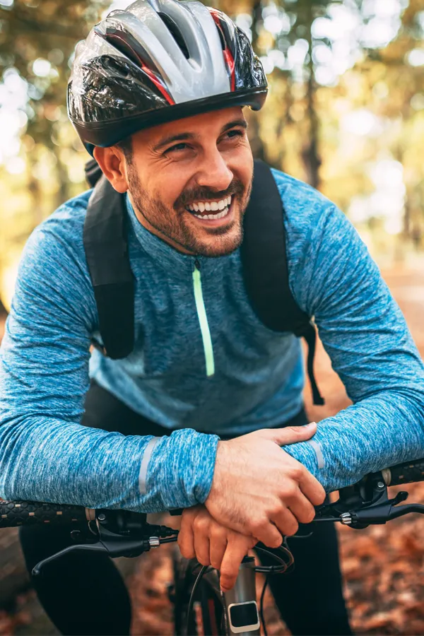 Testosterone-Low-T-Solutions-Treatment A middle-aged man on a trail in cycling clothes is smiling and leaning on his bike's handlebars. Get testosterone for Low T from Anita Petruzzelli, M.D. in Glastonbury.