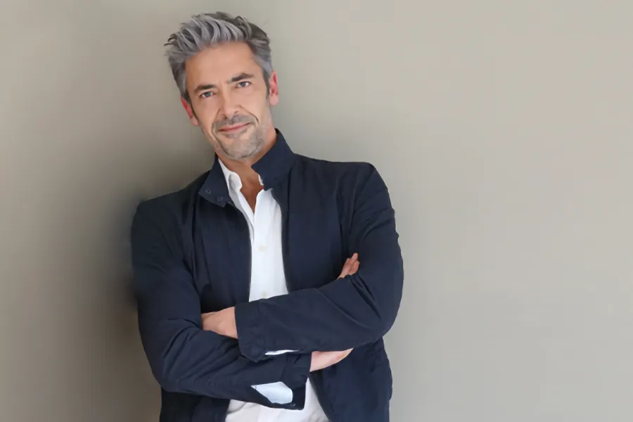 Testosterone-Low-T-Solutionsn-Clinic A middle-aged man in a white shirt and dark blue jacket leans against a gray wall smiling. Get testosterone for Low T from Anita Petruzzelli, M.D. in Glastonbury.
