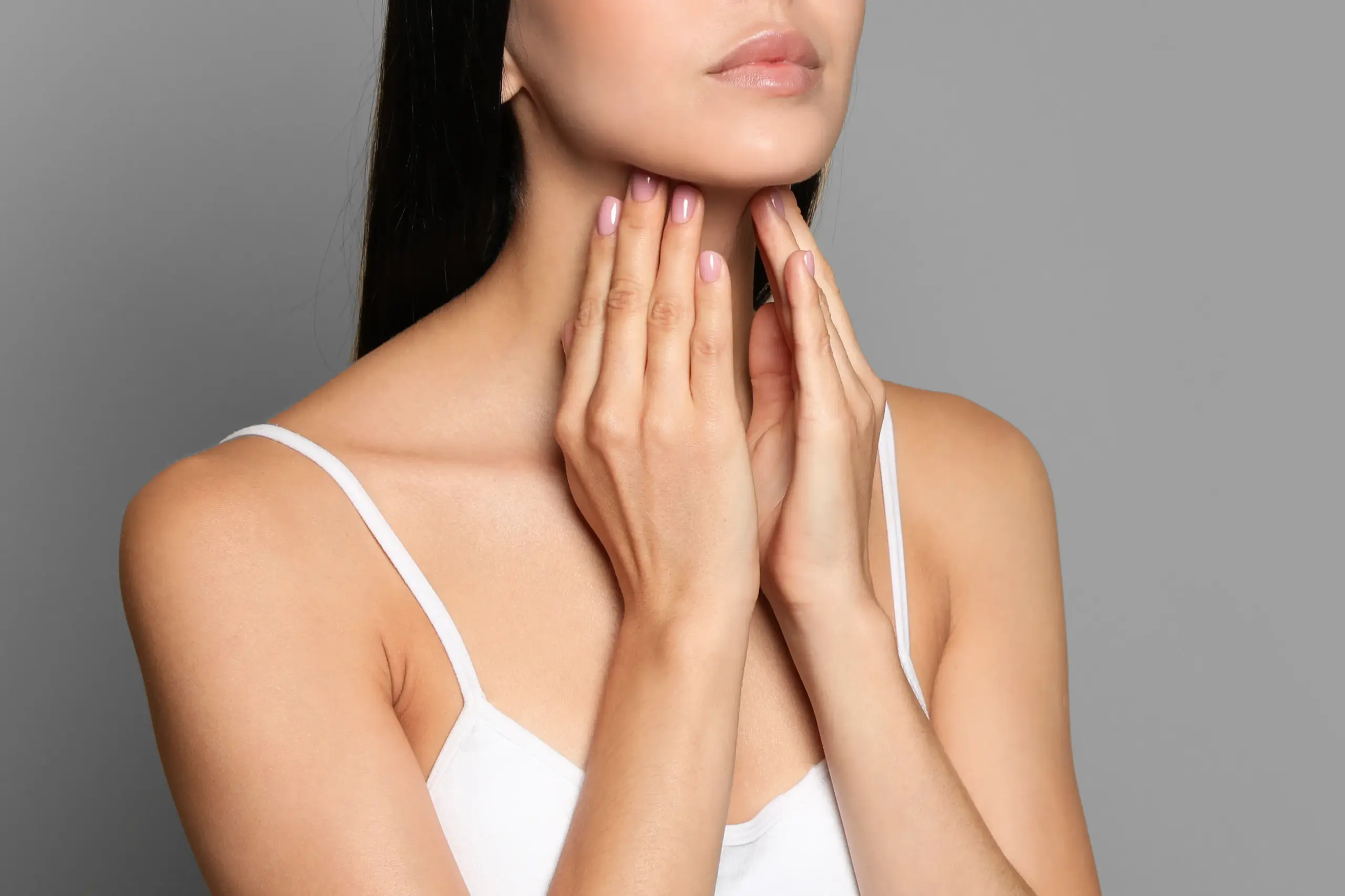 Thyroid-Doctor A woman in a white tank top touches her neck looking for signs of thyroid disorder. Get help for thyroid disorders from Anita Petruzzelli, M.D. in Glastonbury.